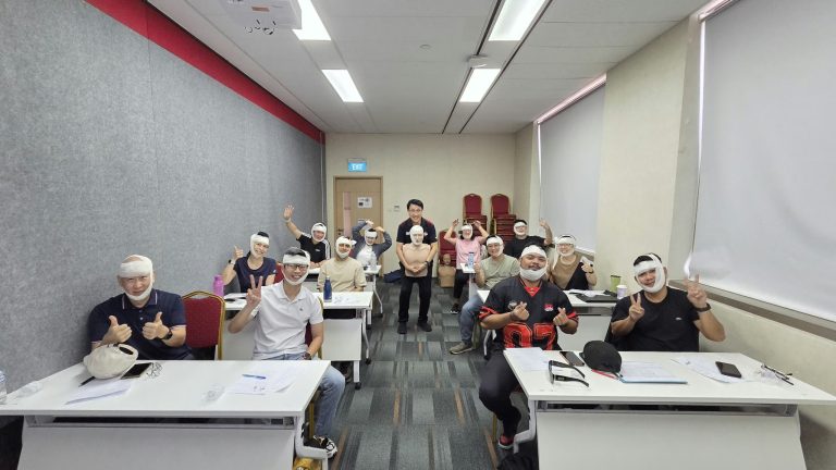 Participants in a first aid training class, posing with their bandaging on